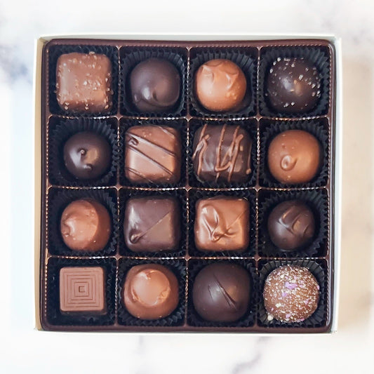 Box of assorted chocolates with different shapes and sizes on a white background