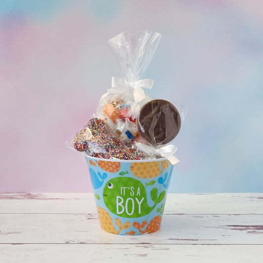 Our "It's a Boy" Baby Basket is a perfect gift for baby showers, new parents, or proud grandparents. Each baby-themed container is filled with a delightful mix of candy favorites including:
8 ounces of soft, chewy salt water taffy in an assortment of classic flavors, milk chocolate nonpareils, and a handmade milk chocolate baby bottle lollipop, all wrapped up and ready to gift.