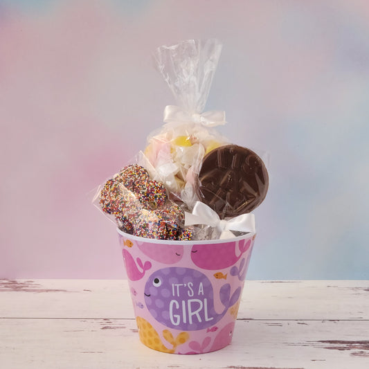 Our "It's a Girl" Baby Basket is a perfect gift for baby showers, new parents, or proud grandparents. Each baby-themed container is filled with a delightful mix of candy favorites including:
8 ounces of soft, chewy salt water taffy in an assortment of classic flavors, milk chocolate nonpareils, and a handmade milk chocolate "It's a Girl" lollipop, all wrapped up and ready to gift.