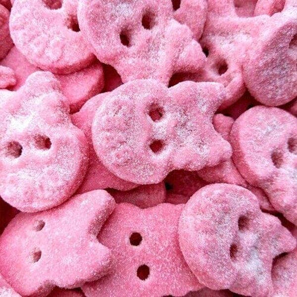 Close-up of pink candy shaped like skulls with a sugary texture.