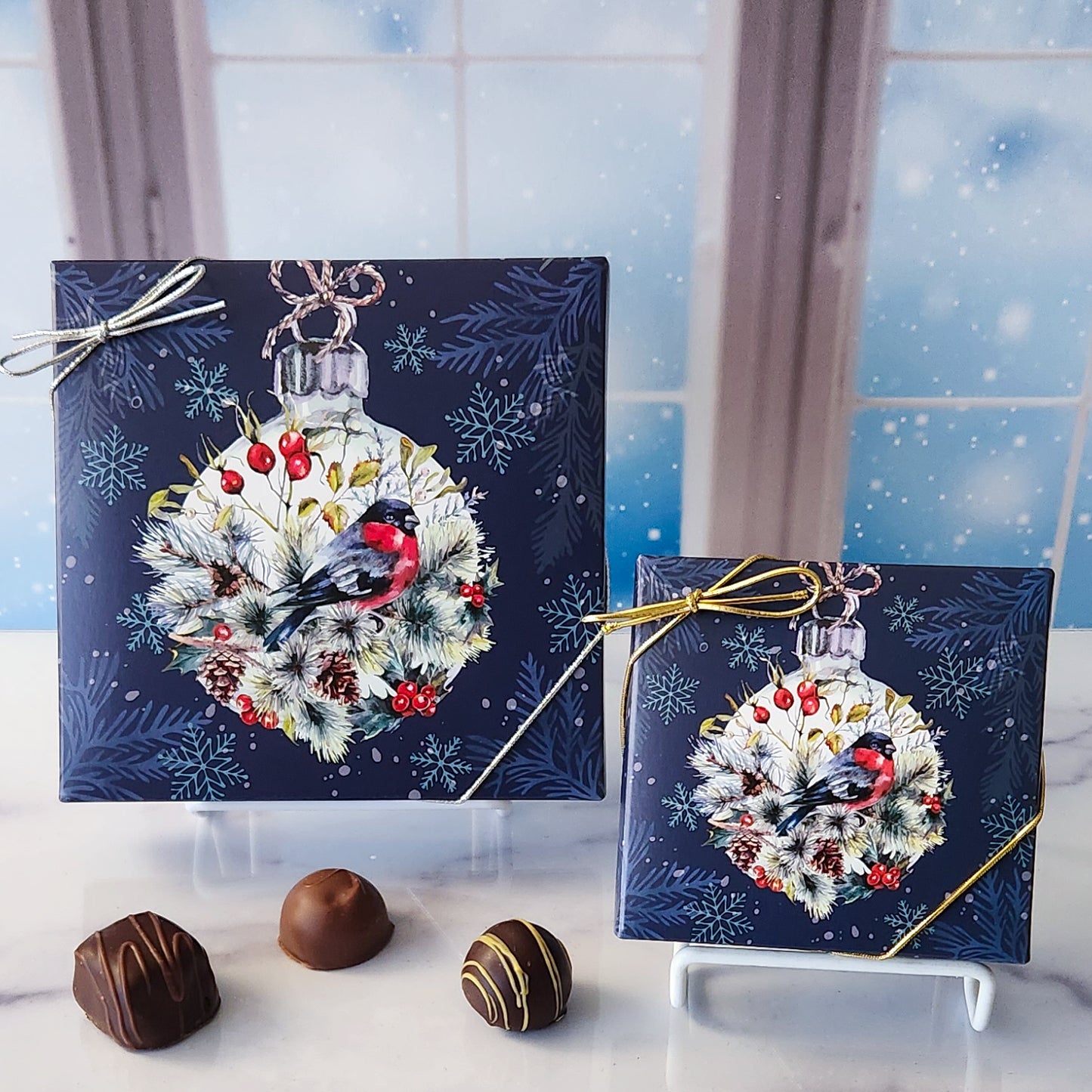 An assortment of our most popular milk and dark chocolate creams, caramels, melt-aways, and truffles all packed inside a box with a beautiful winter bird sitting on an ornament printed on the cover.