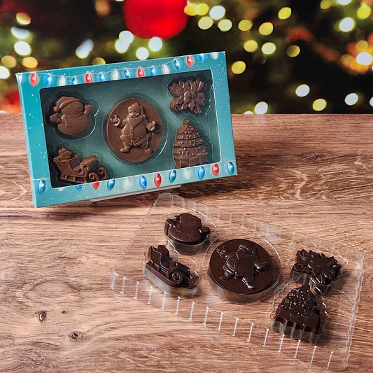 Celebrate the season with our Merry Christmas Chocolate Box Set, filled with holiday cheer in every bite! This charming collection includes beautifully molded chocolates shaped like a jolly Santa, a classic snowman, a festive sleigh, delicate holly, and a shimmering Christmas tree—each crafted to bring the magic of Christmas right to your taste buds. Available in Milk or Dark Chocolate