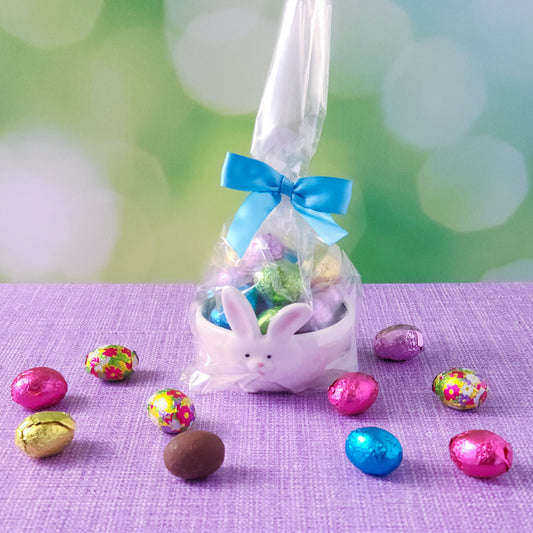 Add a touch of Easter magic with our Cottontails Candy Dish, a delightful bunny-shaped candy dish filled with milk chocolate foils! This adorable ceramic dish features a white exterior with a charming bunny face and ears, while the inside comes in your choice of aqua, pink, or purple. Each dish is beautifully packaged in a clear gift bag and tied with a coordinating bow, making it a perfect Easter gift, festive decoration, or special treat for yourself!