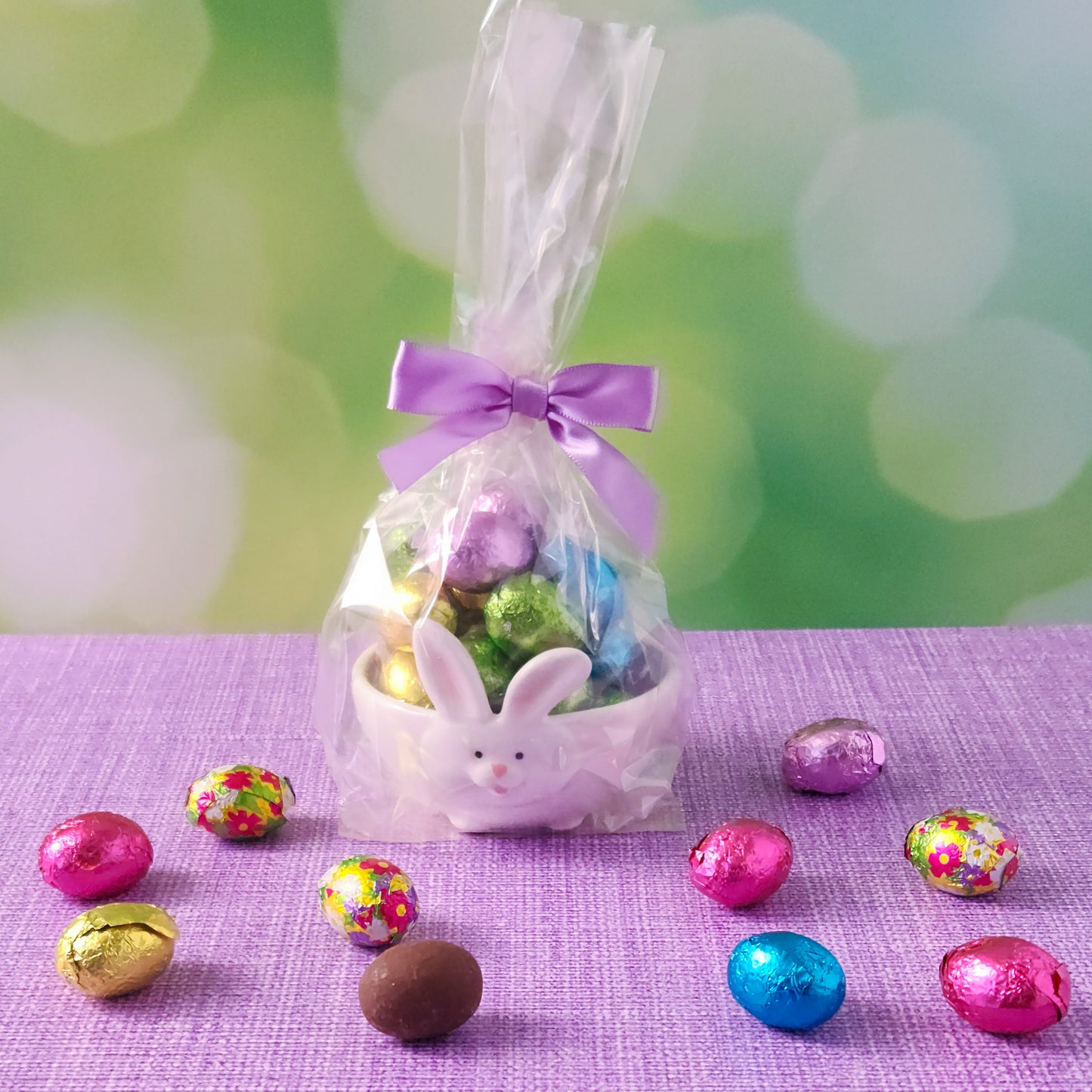 Add a touch of Easter magic with our Cottontails Candy Dish, a delightful bunny-shaped candy dish filled with milk chocolate foils! This adorable ceramic dish features a white exterior with a charming bunny face and ears, while the inside comes in your choice of aqua, pink, or purple. Each dish is beautifully packaged in a clear gift bag and tied with a coordinating bow, making it a perfect Easter gift, festive decoration, or special treat for yourself!