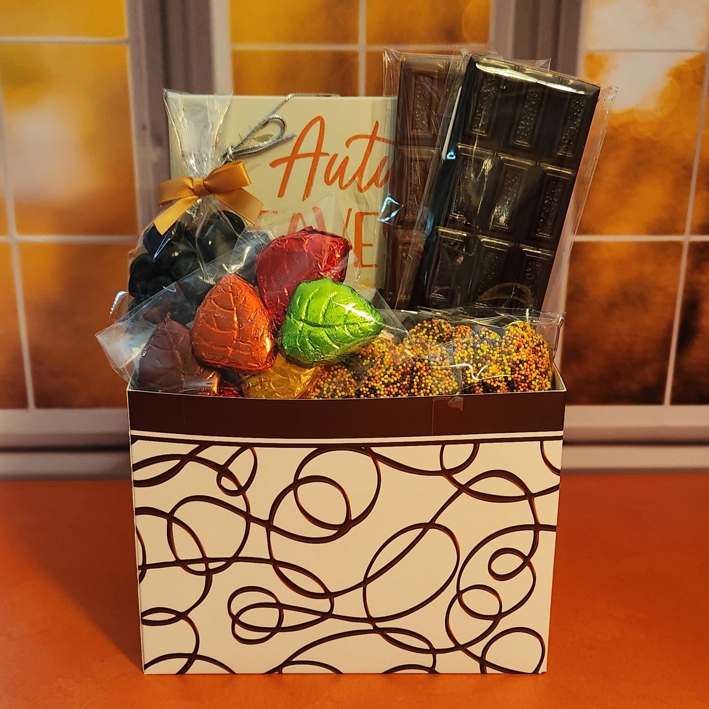 Our Festive Fall Gift Basket features a delectable variety, including dark chocolate cranberries, milk chocolate nonpareils, foiled leaves, and a 16-piece assortment of irresistible chocolates.