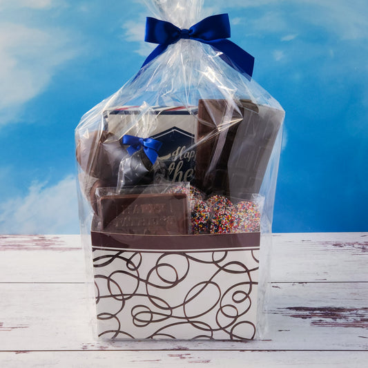 Let Dad know just how awesome he is with our Happy Father’s Day Gift Basket. Inside, he’ll find a 16-piece assortment of our best-selling chocolates—smooth meltaways, rich truffles, creamy caramels, and soft centers. We’ve also added dark chocolate-covered cranberries, chocolate-covered Oreo cookies, and milk chocolate nonpareils for a fun mix of flavors and textures. He’ll also unwrap two classic candy bars—one milk, one dark—and a milk chocolate card that says “Happy Father’s Day.”