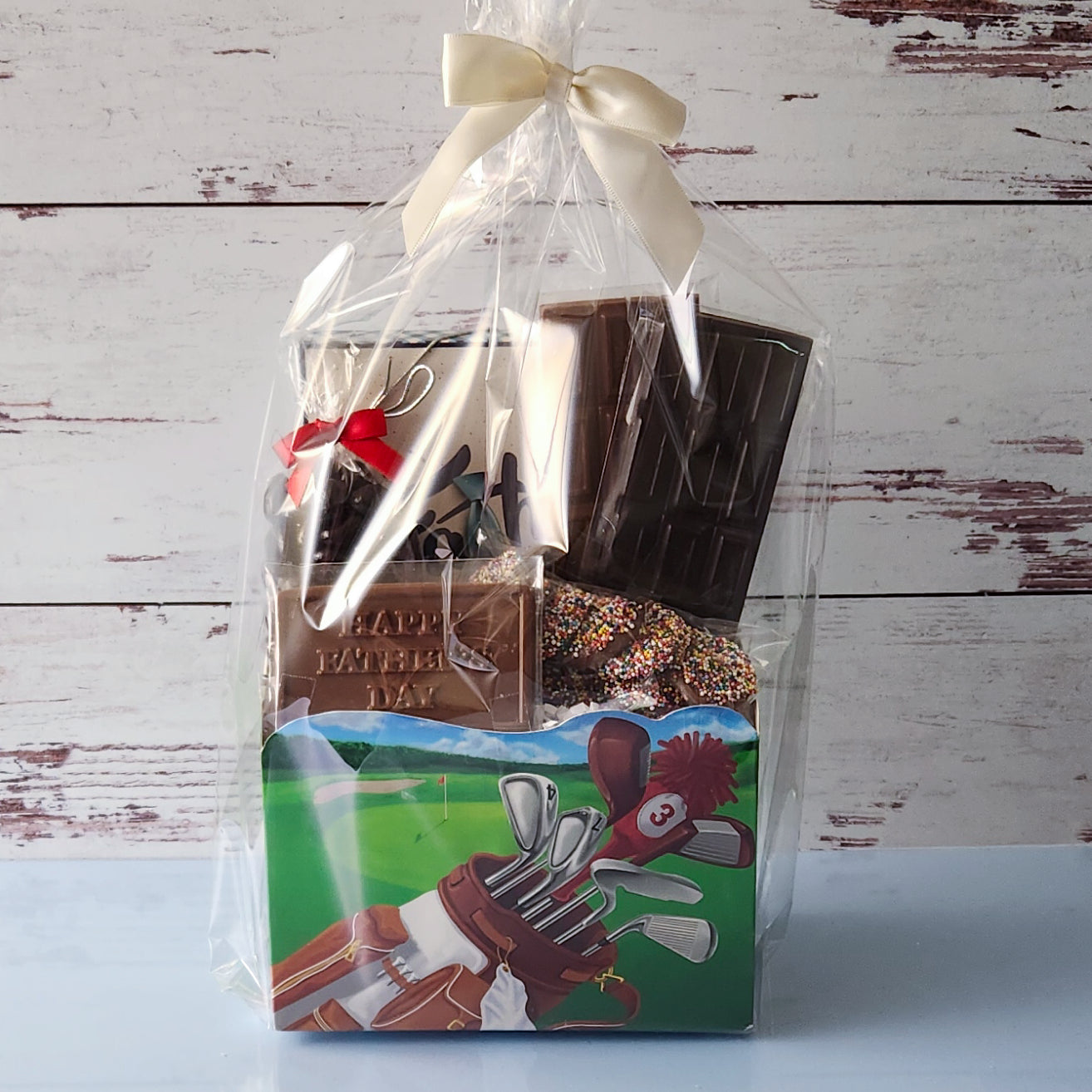 The perfect gift for father's day. A chocolate basket filled with all of dads favorites. Wrapped up in a golf themed basket.