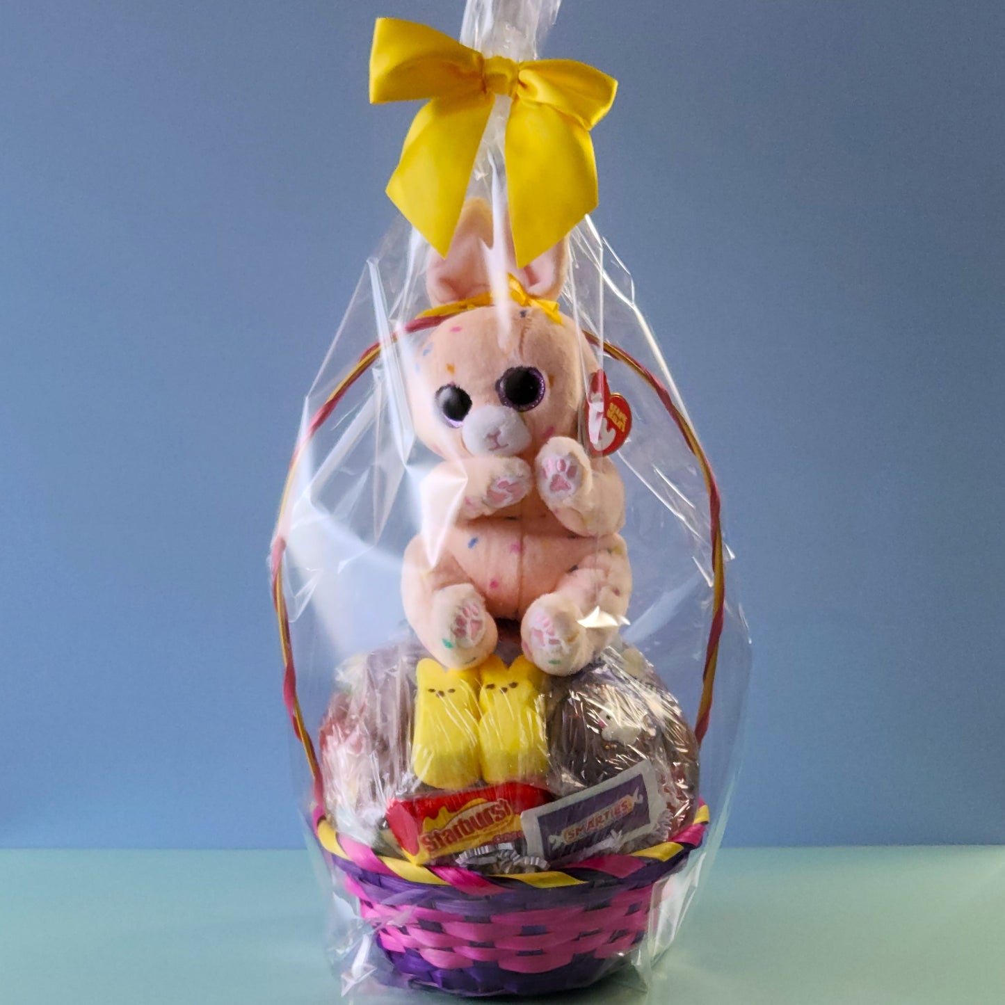 Each basket contains marshmallow peeps, gummy eggs and bunnies, a chocolate covered Easter Oreo, Easter Egg malt balls, jelly beans, a milk chocolate bunnies, lots of yummy kids candy and is topped off with a TY Stuffed Animal Easter Bunny. We finish the basket with overwrap and a bow so that it is ready to gift!
*** Due to the limited quantity of baskets we cannot guarantee specific colors. Photos are for example only and basket color may differ from the ones shown.