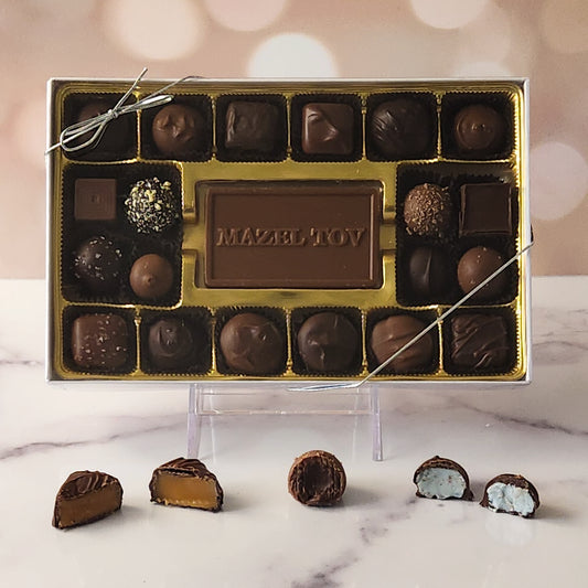 Celebrate special moments with our 20-piece Mazel Tov Candy Box! Inside, a beautifully crafted milk chocolate card that says "Mazel Tov" is surrounded by an irresistible selection of milk and dark chocolate soft center creams, decadent truffles, and luscious caramels. It's the perfect way to share your best wishes and add sweetness to any joyous occasion!