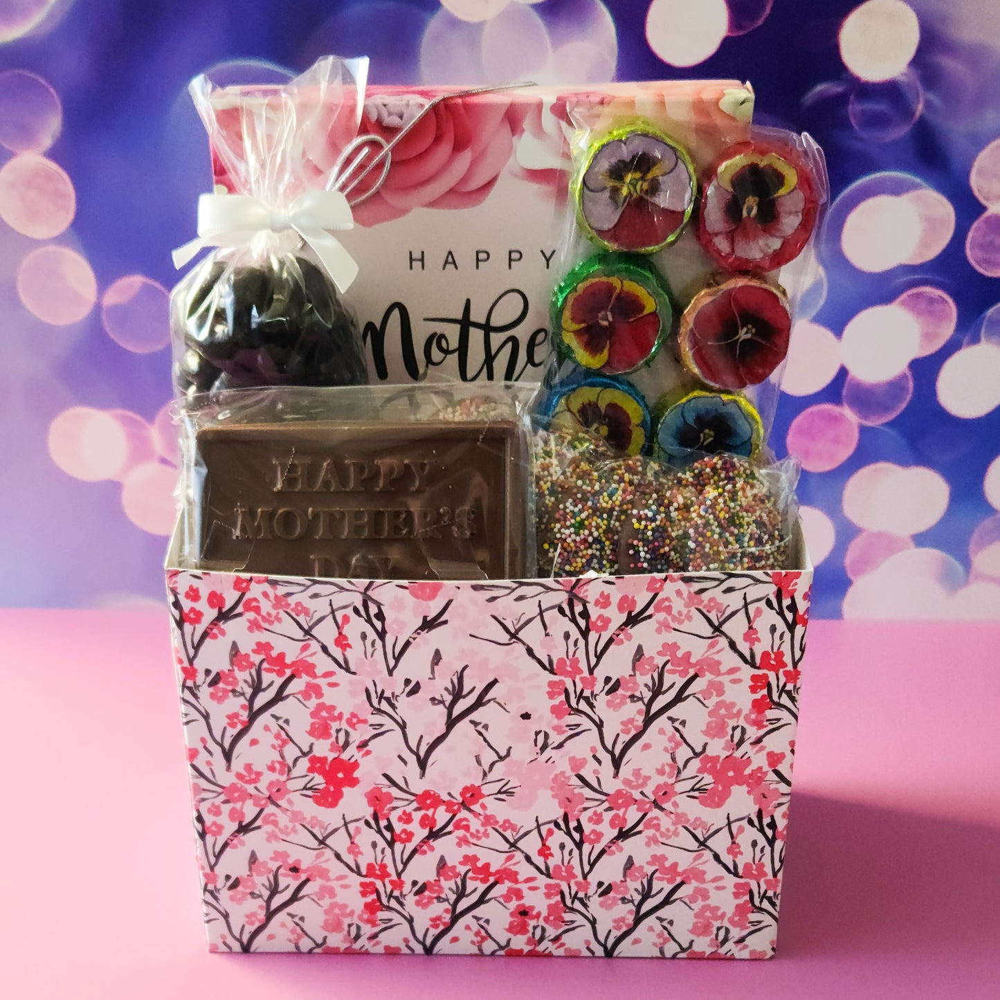 A gift basket themed for mom. Filled with dark chocolate cranberries, milk chocolate nonpareils, flowers and a chocolate Mothers day card along with a 16 piece chocolate assortment.