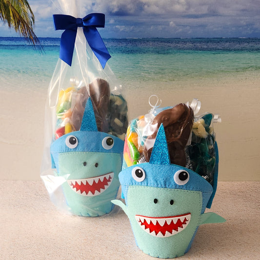 A felt basket in the shape of a shark. Filled to the brim with Gummi Worms, Baby Gummi Sharks, Salt Water Taffy and a Milk Chocolate Shark Pop.