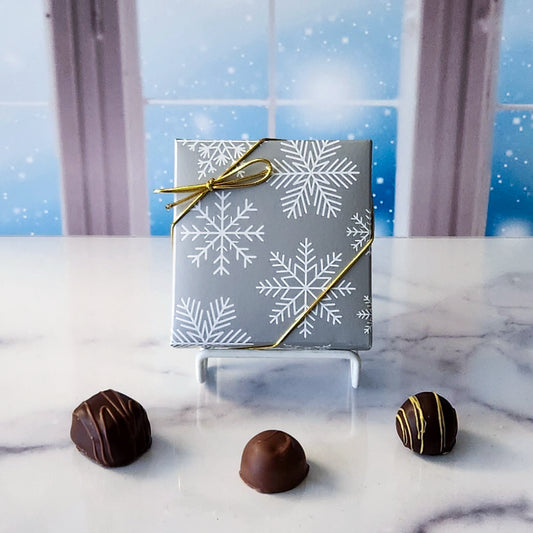 An assortment of our most popular milk and dark chocolate creams, caramels, melt-aways, and truffles all packed inside a box with an elegant snowflake pattern on the cover.