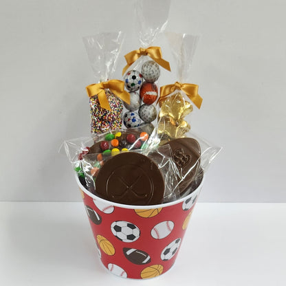 Sports themed chocolate gift basket featuring Foil Sports Balls, M & M Pretzel, Foil Gold Stars, Milk Chocolate Nonpareils, a Milk Chocolate Hockey Puck and Football