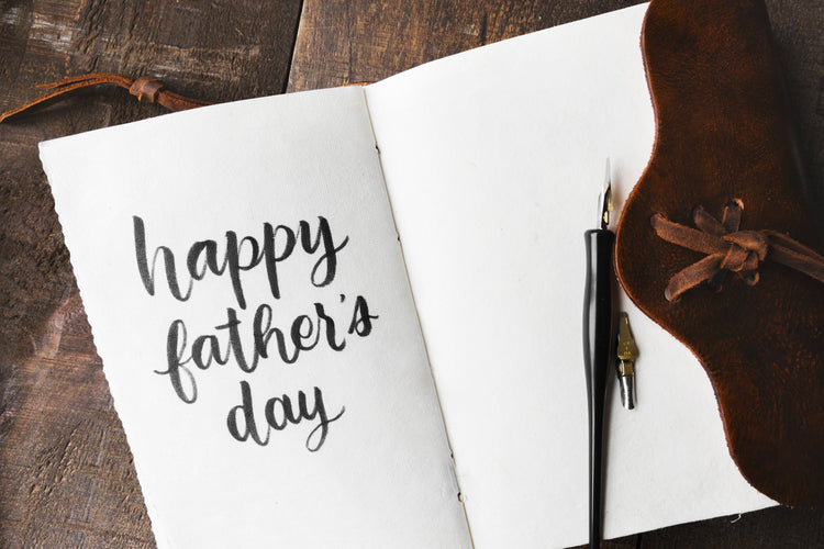 The message Happy Father's Day written by hand in a leather journal.