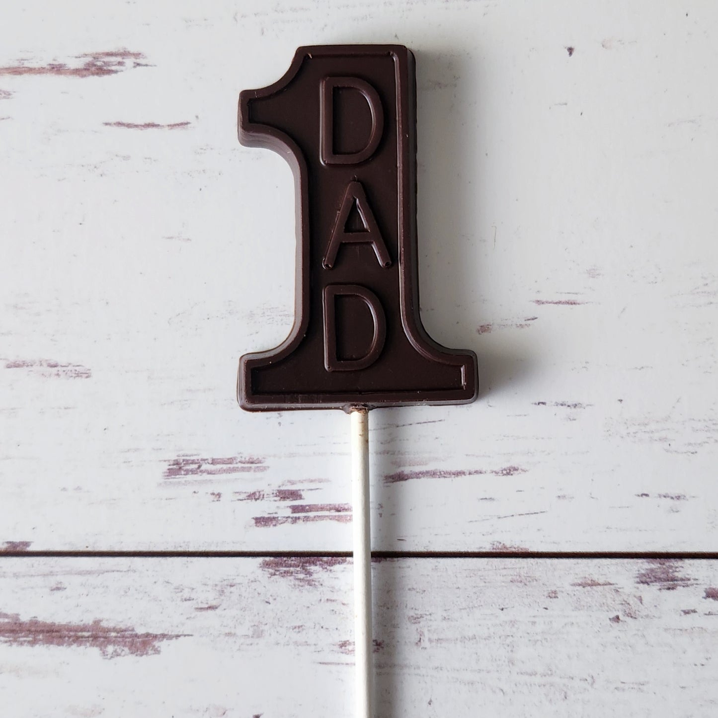 Treat Dad to our #1 Dad Dark Chocolate Lollipop this Father's Day! Crafted in the shape of the number 1 and featuring "Dad," this rich dark chocolate delight makes a unique and memorable gift. Show your appreciation with this sweet way to celebrate the best dad ever!