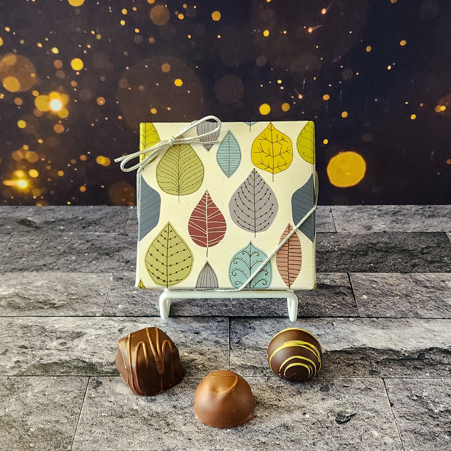 An assortment of our most popular milk and dark chocolate creams, caramels, melt-aways, and truffles all packed inside a box with a whimsical leaf pattern printed on it.