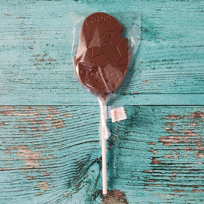 Chocolate lollipop with a tag on a textured blue wooden surface