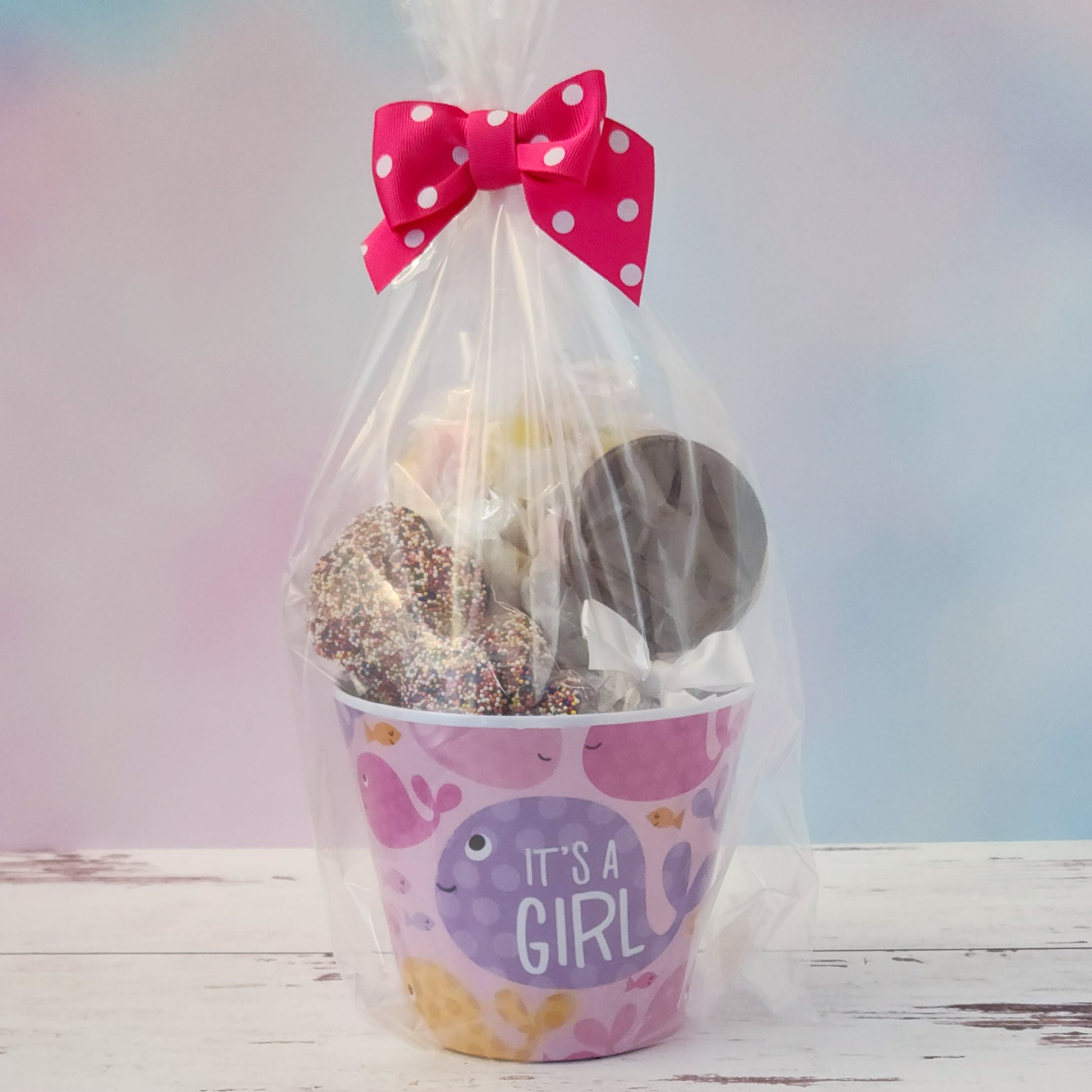 Our "It's a Girl" Baby Basket is a perfect gift for baby showers, new parents, or proud grandparents. Each baby-themed container is filled with a delightful mix of candy favorites including:
8 ounces of soft, chewy salt water taffy in an assortment of classic flavors, milk chocolate nonpareils, and a handmade milk chocolate "It's a Girl" lollipop, all wrapped up and ready to gift.