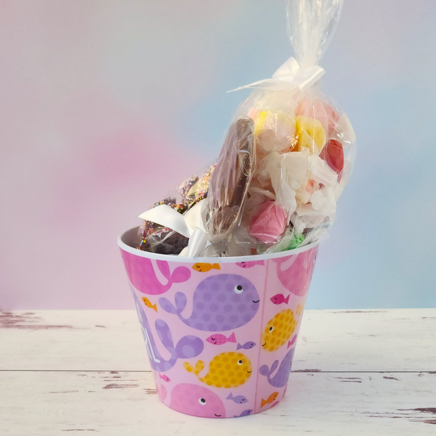 Our "It's a Girl" Baby Basket is a perfect gift for baby showers, new parents, or proud grandparents. Each baby-themed container is filled with a delightful mix of candy favorites including:
8 ounces of soft, chewy salt water taffy in an assortment of classic flavors, milk chocolate nonpareils, and a handmade milk chocolate "It's a Girl" lollipop, all wrapped up and ready to gift.