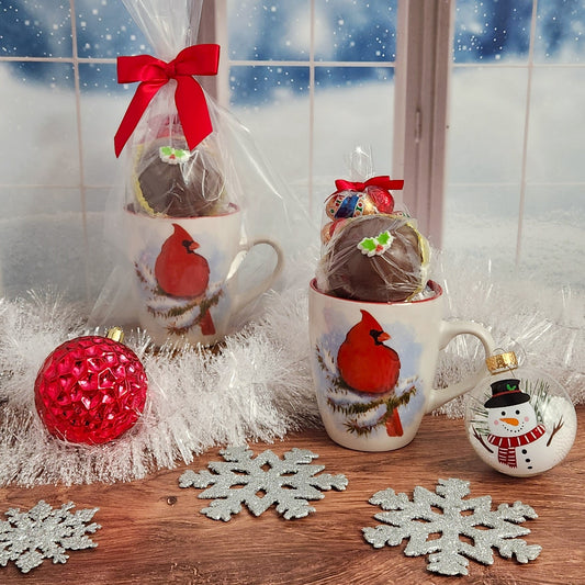 The Cardinal on Winter Branch Gift Mug from Stage Stop Candy includes 4 oz. of milk chocolate foiled ornaments and a Hot Cocoa Bomb - Ideal for a cozy winter evening by the fire, beautifully wrapped and ready to spread Holiday cheer!
