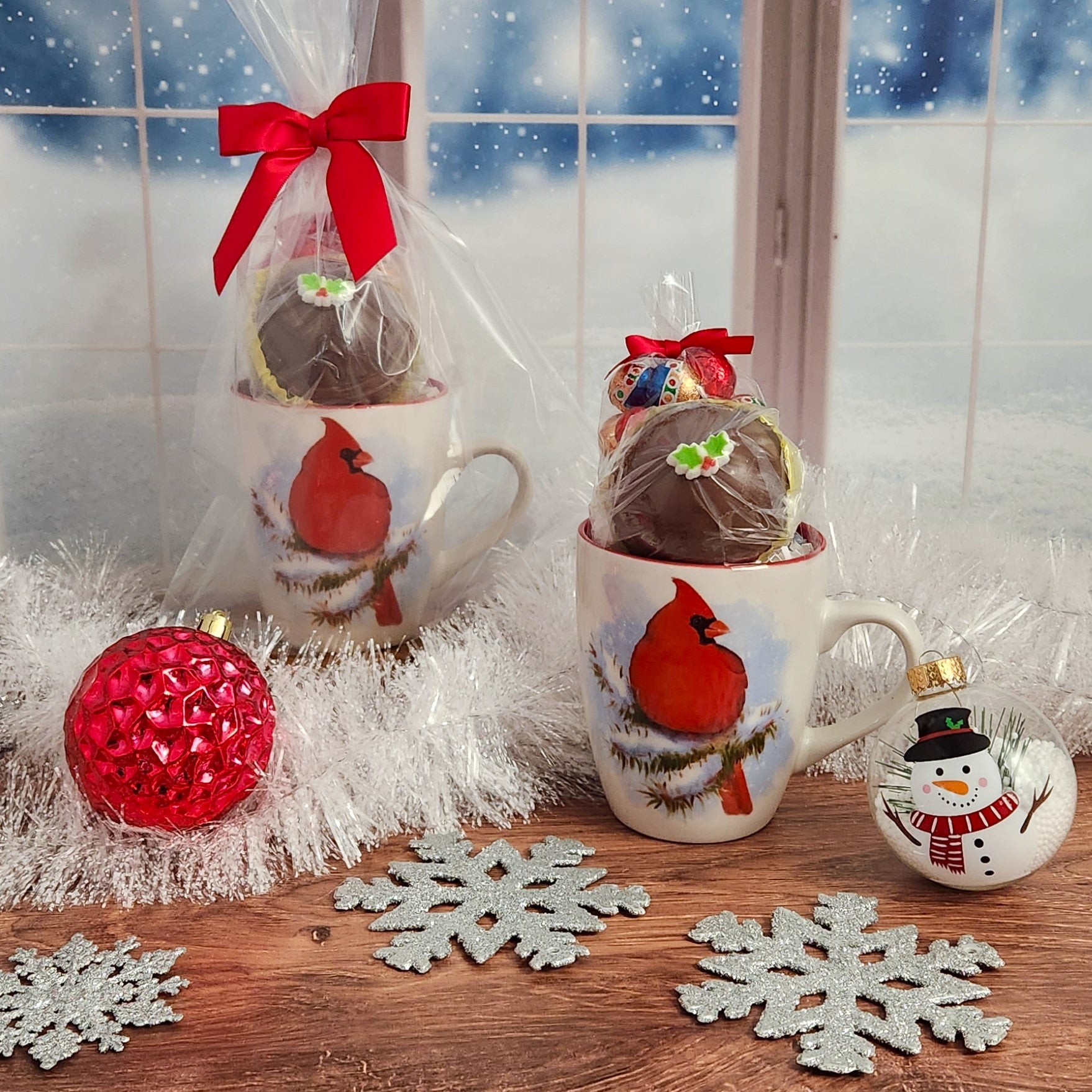 The Cardinal on Winter Branch Gift Mug from Stage Stop Candy includes 4 oz. of milk chocolate foiled ornaments and a Hot Cocoa Bomb - Ideal for a cozy winter evening by the fire, beautifully wrapped and ready to spread Holiday cheer!