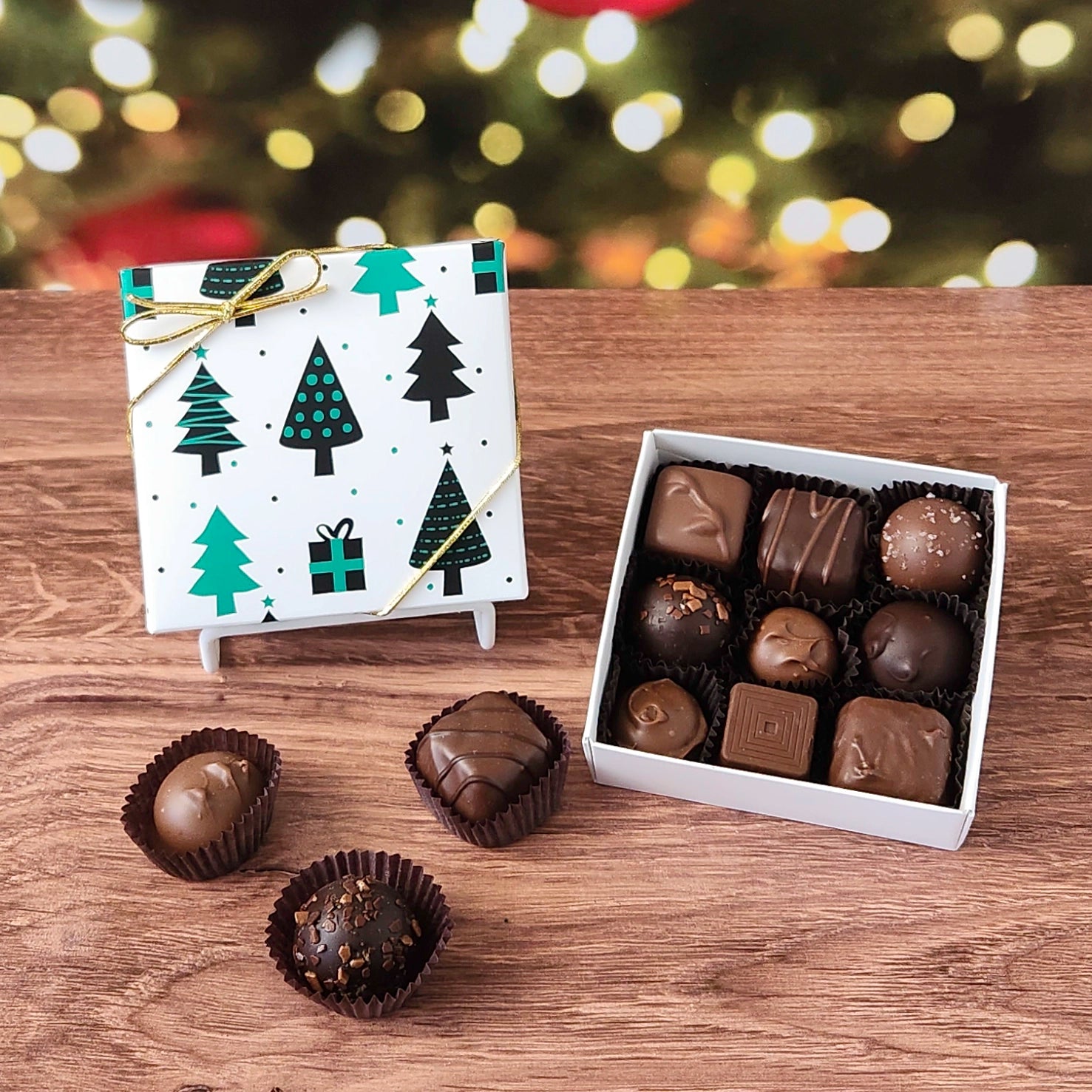 Box of chocolates with a decorative Christmas-themed cover on a wooden surface.
