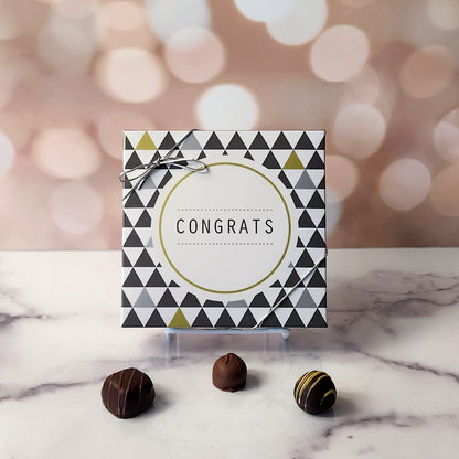 An assortment of our most popular milk and dark chocolate creams, caramels, melt-aways, and truffles all packed inside a festive box. On the cover of the box the word CONGRATS is printed surrounded by a grey and gold motif.