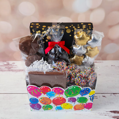 Make life’s big moments even sweeter with our Celebrate Gift Basket!
Inside, you’ll find a mix of gold and silver foiled milk chocolate stars, two chocolate-covered Oreo cookies, and classic milk chocolate nonpareils. A milk chocolate card that says “Congratulations”, dark chocolate-covered cranberries and a luxurious 16-piece assortment of creams, caramels, meltaways, and truffles. All overwrapped with a bow and ready for gifting!