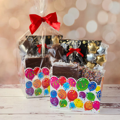 Make life’s big moments even sweeter with our Celebrate Gift Basket!
Inside, you’ll find a mix of gold and silver foiled milk chocolate stars, two chocolate-covered Oreo cookies, and classic milk chocolate nonpareils. A milk chocolate card that says “Congratulations”, dark chocolate-covered cranberries and a luxurious 16-piece assortment of creams, caramels, meltaways, and truffles. All overwrapped with a bow and ready for gifting!