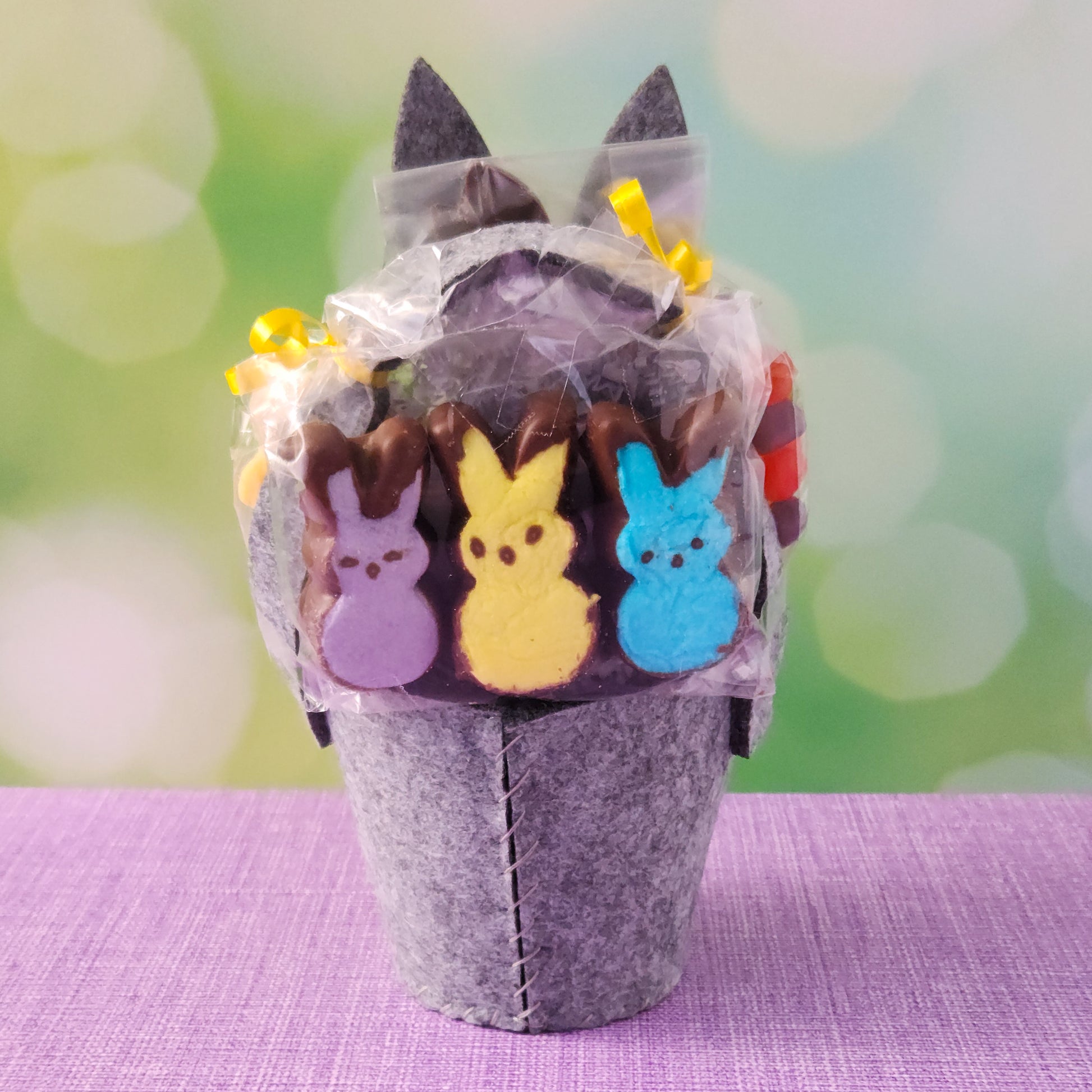 This adorable felt bunny-shaped basket is filled with a delicious assortment of Chocolate-Dipped Marshmallow Peeps, fruity Jelly Beans, Sanded Gummi Bunnies, and a Chocolate Bunny Favor. Wrapped in overwrap and finished with a beautiful bow