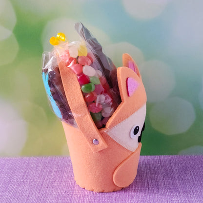 The basket base is an adorable felt fox, filled with an irresistible assortment of Chocolate-Dipped Marshmallow Peeps, fruity Jelly Beans, Sanded Gummi Bunnies, and a delicious Chocolate Bunny Favor. Finished with overwrap and a festive bow, this basket is ready to gift