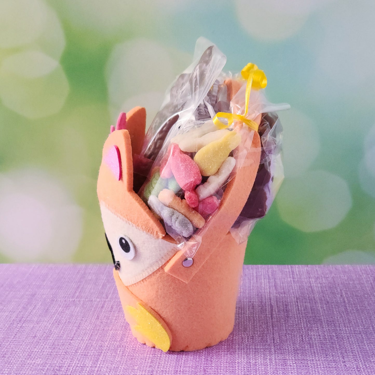 The basket base is an adorable felt fox, filled with an irresistible assortment of Chocolate-Dipped Marshmallow Peeps, fruity Jelly Beans, Sanded Gummi Bunnies, and a delicious Chocolate Bunny Favor. Finished with overwrap and a festive bow, this basket is ready to gift