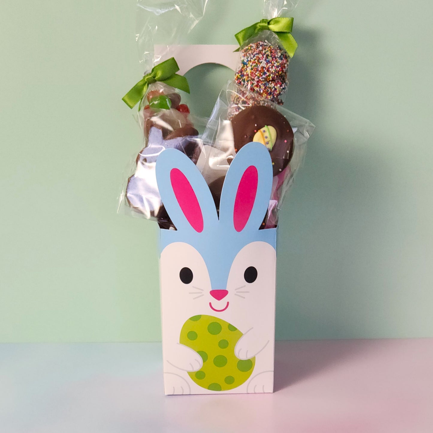 Blue Bunny Door Hanger Gift Basket.
Inside you will find Jelly Beans, Milk Chocolate Nonpareils, Milk Chocolate Oreos dressed up with an Easter sugar decoration, and Chocolate Covered Peeps!
The box is designed to hang on a door knob.