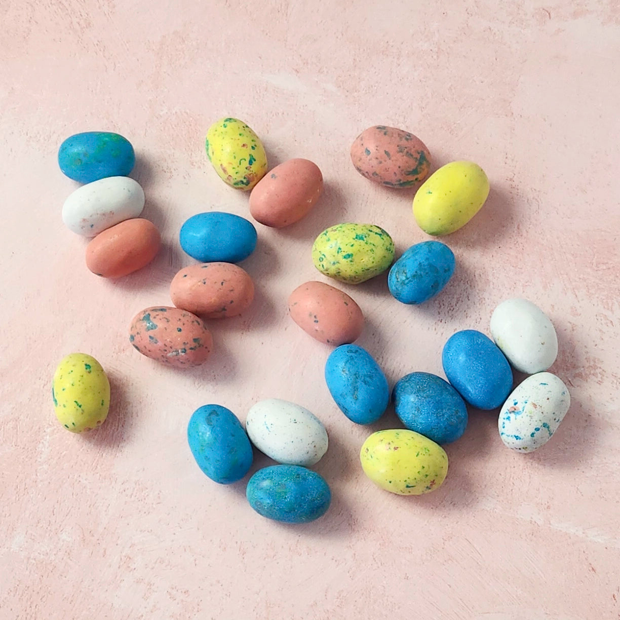 Colorful chocolate Easter eggs on a beige surface