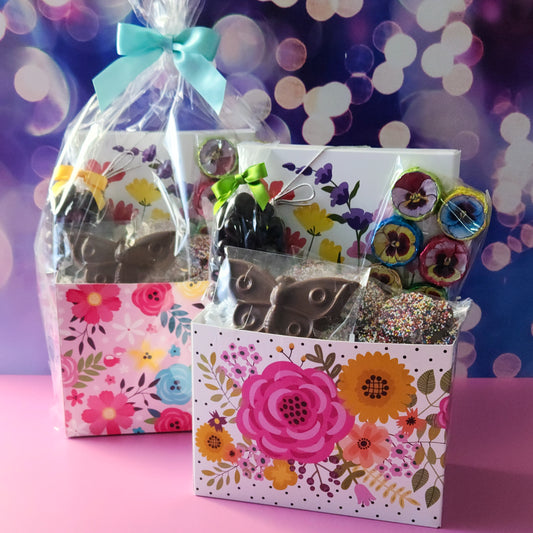 A springtime themed basket filled with chocolate covered cranberries, milk chocolate foiled flowers, nonpareils, a chocolate butterfly and a 16 piece chocolate assortment.