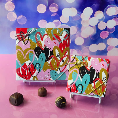 An assortment of our most popular milk and dark chocolate creams, caramels, melt-aways, and truffles all packed inside a festive box. On the cover of the box colorful fluttering hearts are printed.