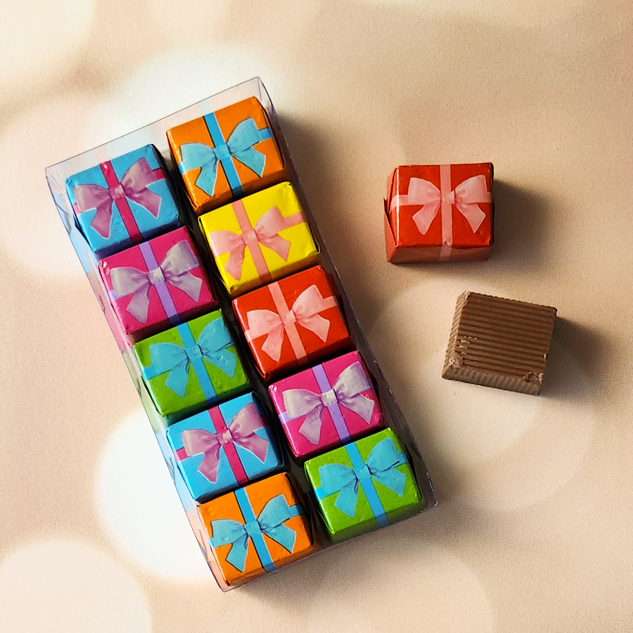 10 Bite sized milk chocolate pieces are wrapped in decorative foil to look like little gifts. Packed in a clear box.