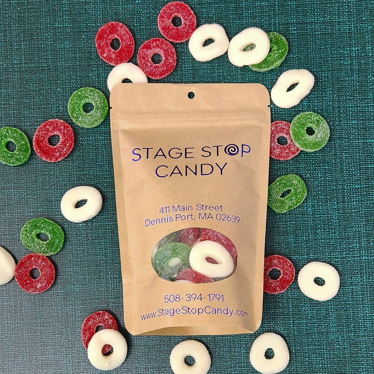 Gummi Wreaths, top-down view of the kraft bag on teal, ringed by sugar-sanded red, green and white rings