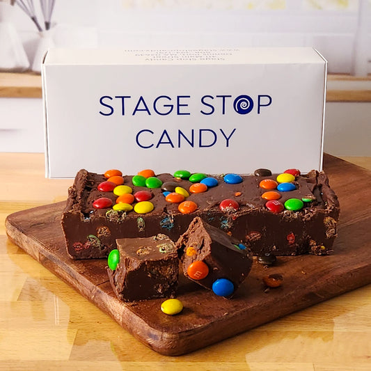 Made in a traditional copper kettle, this gourmet treat features a rich chocolate fudge base generously mixed with colorful M&amp;M's, creating a fun and flavorful combination.