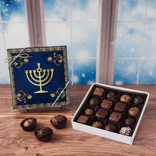 16 piece box of chocolates with a decorative Hanukkah-themed cover on a wooden surface and snowy background.