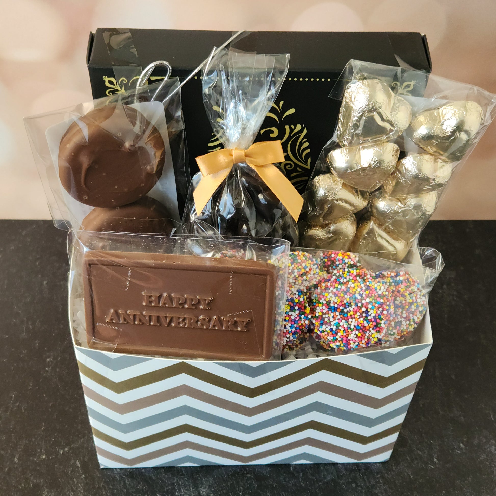 Happy Anniversary Gift Basket.
foiled milk chocolate hearts, dark chocolate–covered cranberries, milk chocolate‑covered Oreos and milk chocolate nonpareils. Topped with a whimsical milk chocolate card that reads “Happy Anniversary,” it’s a heartfelt way to express your love. The centerpiece is a 16‑piece gift box filled with an assortment of creams, caramels, meltaways, and truffles. 