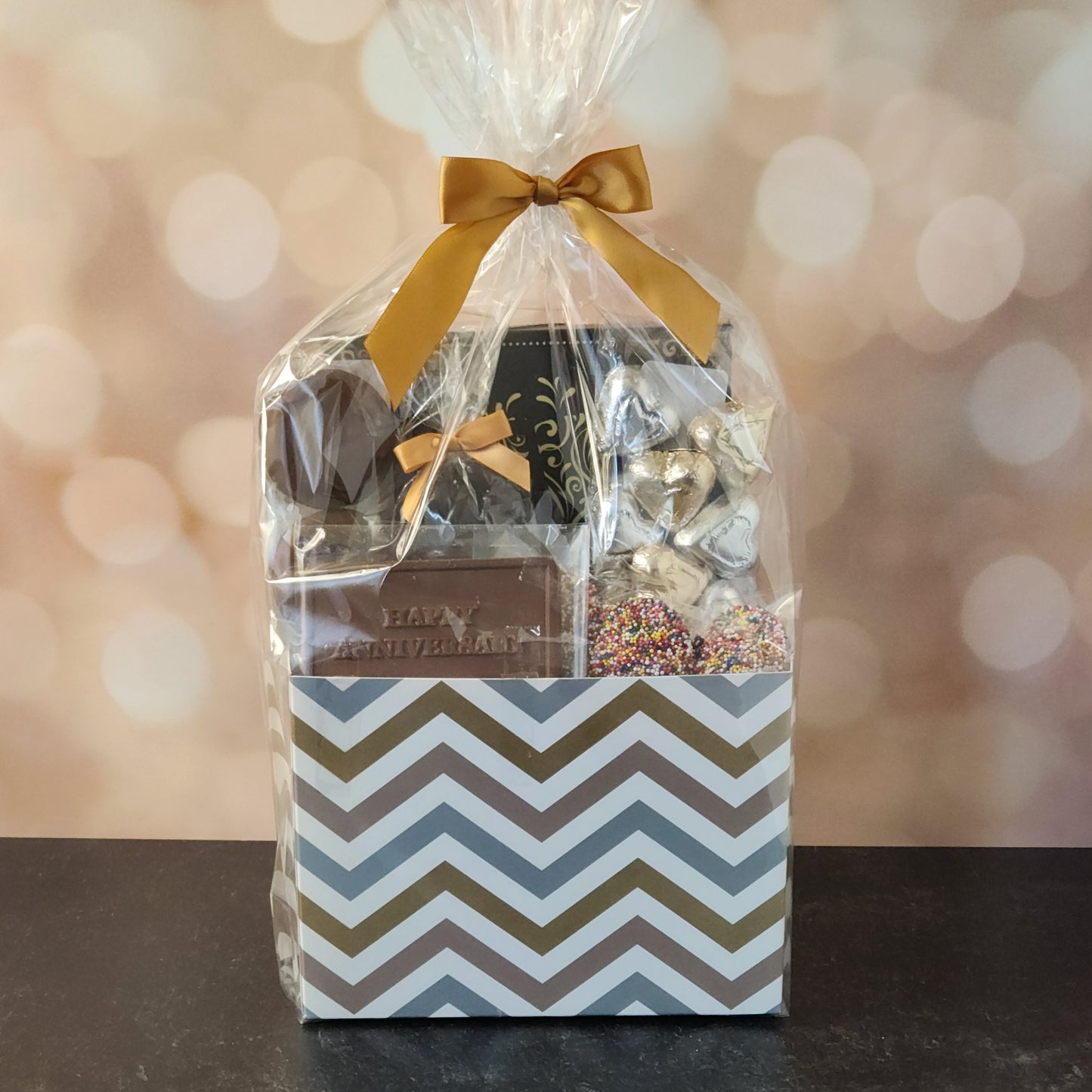 Happy Anniversary Gift Basket.
foiled milk chocolate hearts, dark chocolate–covered cranberries, milk chocolate‑covered Oreos and milk chocolate nonpareils. Topped with a whimsical milk chocolate card that reads “Happy Anniversary,” it’s a heartfelt way to express your love. The centerpiece is a 16‑piece gift box filled with an assortment of creams, caramels, meltaways, and truffles. 