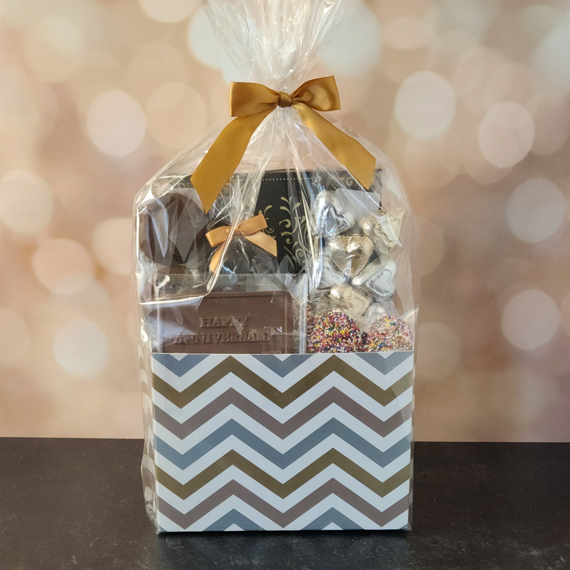 Happy Anniversary Gift Basket.
foiled milk chocolate hearts, dark chocolate–covered cranberries, milk chocolate‑covered Oreos and milk chocolate nonpareils. Topped with a whimsical milk chocolate card that reads “Happy Anniversary,” it’s a heartfelt way to express your love. The centerpiece is a 16‑piece gift box filled with an assortment of creams, caramels, meltaways, and truffles. 