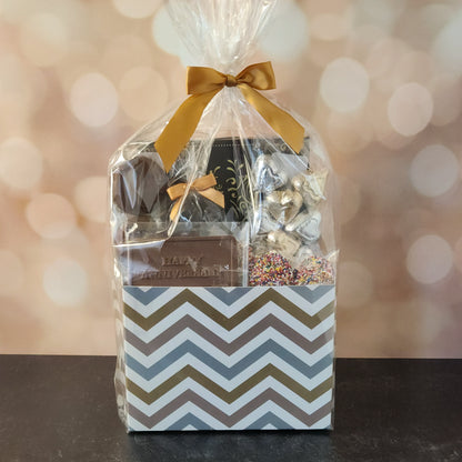 Happy Anniversary Gift Basket.
foiled milk chocolate hearts, dark chocolate–covered cranberries, milk chocolate‑covered Oreos and milk chocolate nonpareils. Topped with a whimsical milk chocolate card that reads “Happy Anniversary,” it’s a heartfelt way to express your love. The centerpiece is a 16‑piece gift box filled with an assortment of creams, caramels, meltaways, and truffles. 