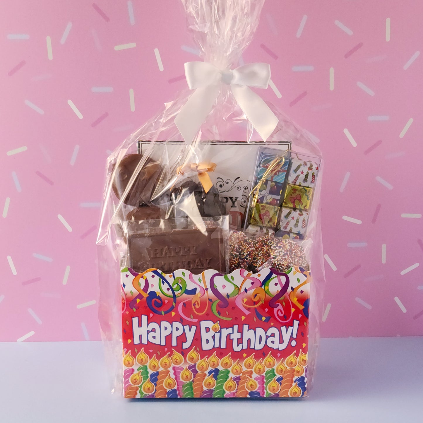 Make birthdays extra special with our Birthday Gift Basket, a delightful assortment of handcrafted chocolates that’s sure to bring a smile to any chocolate lover’s face! Packed with a delicious mix of milk and dark chocolate treats. 
16-Piece Milk and Dark Chocolate Assortment, Milk Chocolate "Happy Birthday" Card, Milk Chocolate Covered Oreos, Milk Chocolate Nonpareils & Foiled Presents, and Dark Chocolate Covered Cranberries all overwrapped and tied with a bow, this basket is ready to gift.