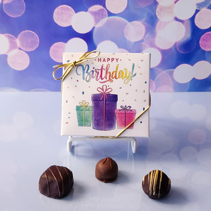 An assortment of our most popular milk and dark chocolate creams, caramels, melt-aways, and truffles all packed inside a festive box. The cover is printed with  the saying Happy Birthday sitting a top a pile of presents.