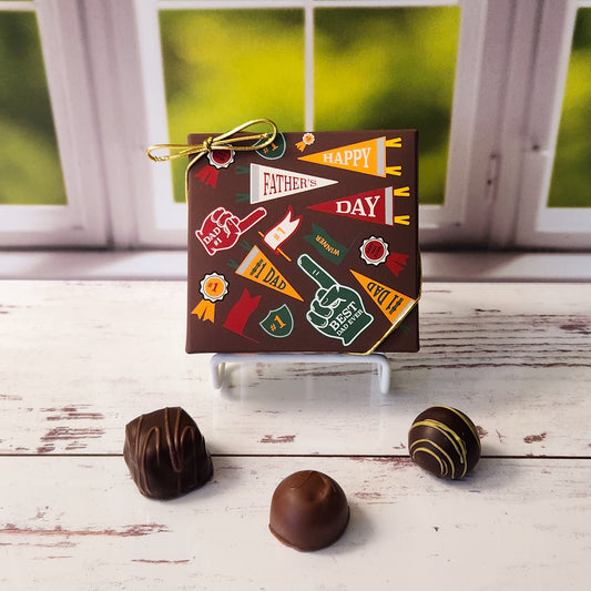 An assortment of our most popular milk and dark chocolate creams, caramels, melt-aways, and truffles all packed inside a box printed with the words Happy Father's Day with a sports theme.