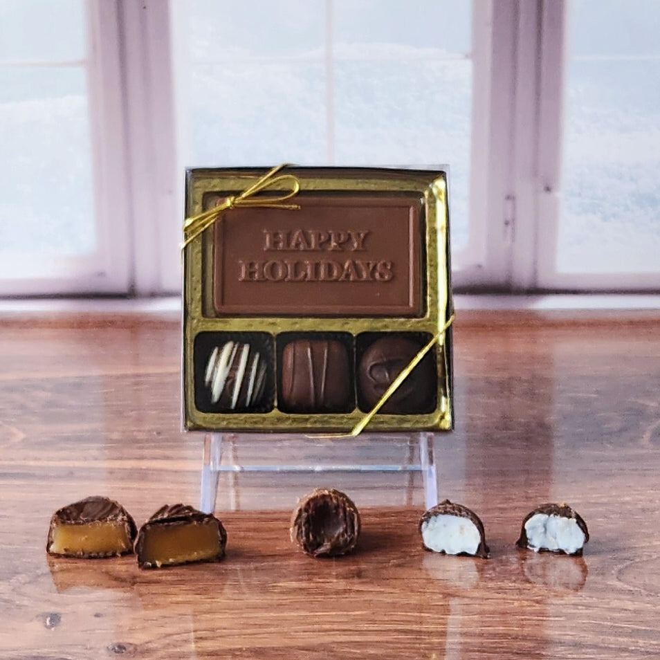 Spread festive cheer with our 3-piece Happy Holidays Candy Box! Inside, a beautifully crafted milk chocolate card that says "Happy Holidays" is paired with a smooth soft center cream, an indulgent truffle, and a delicious caramel. It's the perfect small treat to sweeten the season and share joy with loved ones!