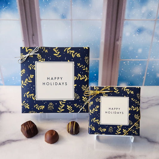 An assortment of our most popular milk and dark chocolate creams, caramels, melt-aways, and truffles all packed inside a box with a Navy Border around the words "Happy Holidays"