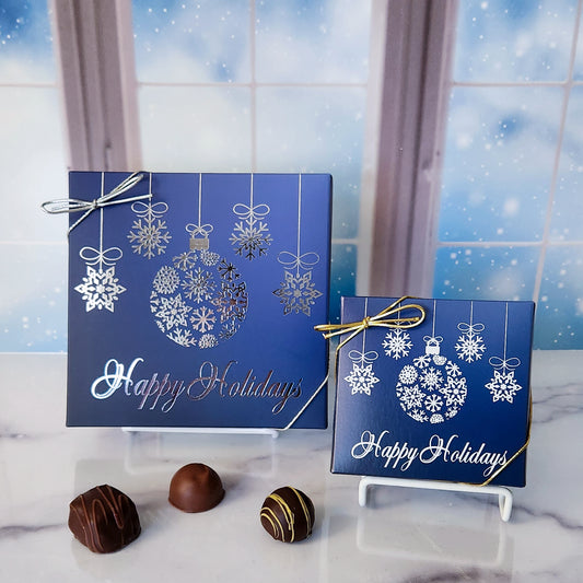 An assortment of our most popular milk and dark chocolate creams, caramels, melt-aways, and truffles all packed inside a box with the words "Happy Holidays" and decorated with pretty ornaments printed on the cover.